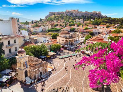 Skyline of Athens with Monastiraki square, Church of Pantanassa and Acropolis hill during summer sunny day. Athens, Greece. Pink bougainvillea flower in the foreground